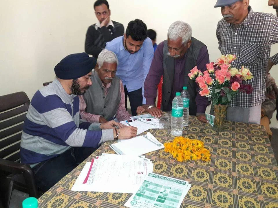 Dr. Bhupinder Arora consulting elderly individuals during a health camp